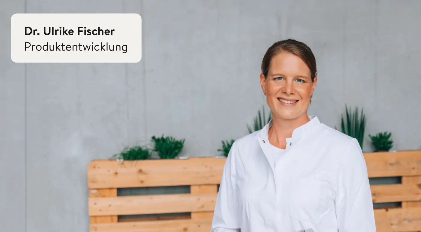 Frau grinst in die kamera. Sie trägt einen weißen Kittel oder Hemd. In der Ecke steht der Titel "Dr. Ulrike Fischer. Produktentwicklung"